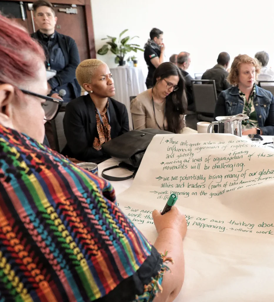A person in a colourful shawl writes on a large sheet of paper