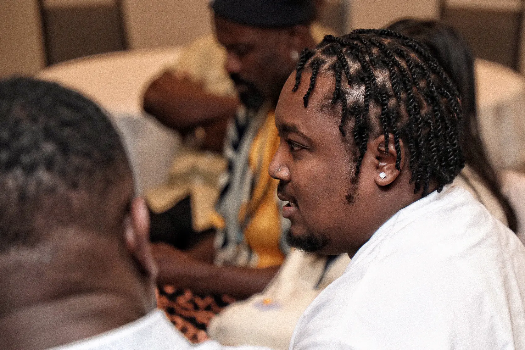 A person seated at a table looks into the distance