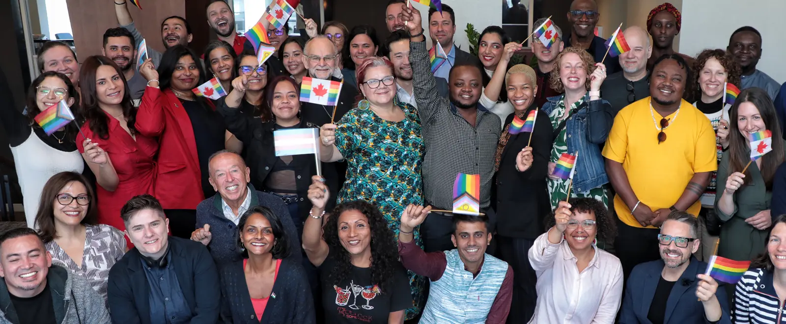 A group of people smile and wave pride flags